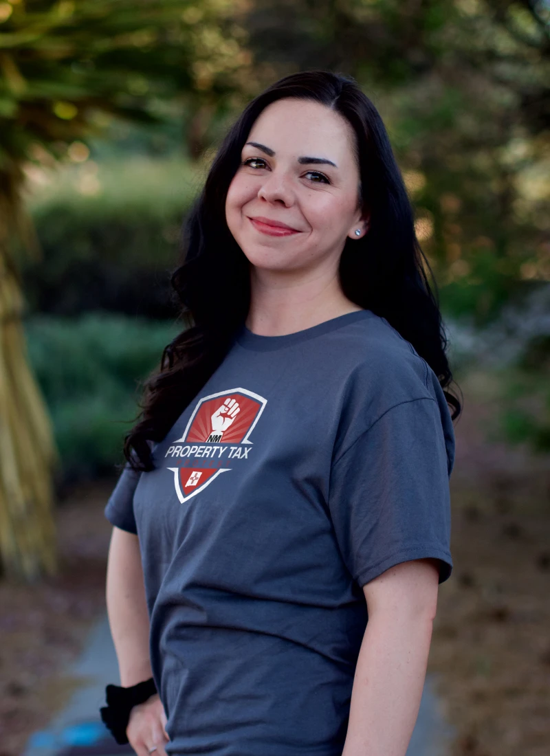 Emma, Client Relations Manager at NM Property Tax Protest, smiling in branded company shirt