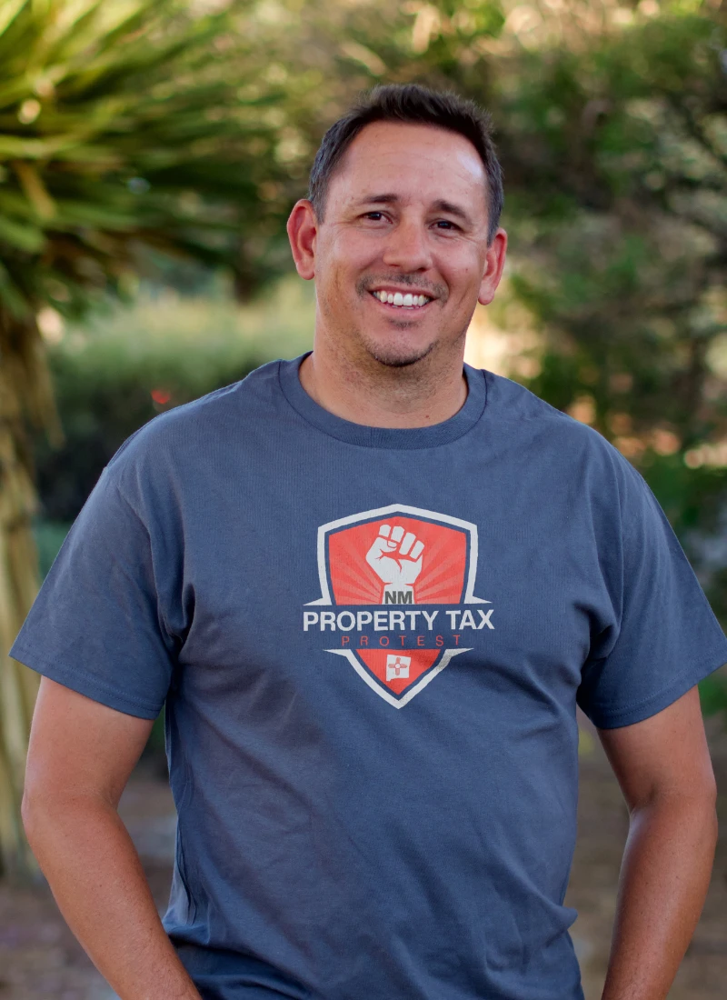 Peter Cochran, Comparable Property Specialist at NM Property Tax Protest, smiling in company shirt